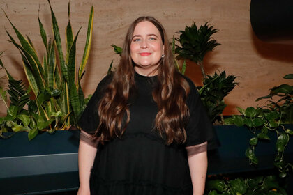 Aidy Bryant wearing a black dress and smiling at the camera