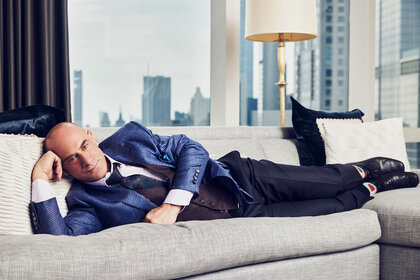 Chris Meloni laying on a couch looking into the camera