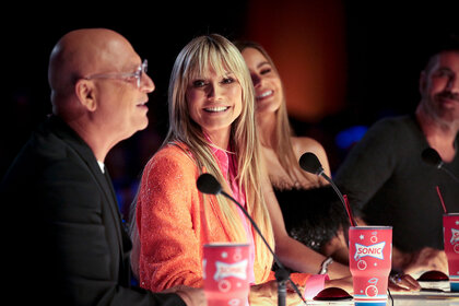 Heidi Klum smiling while seated with the other judges