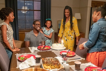 Randall seated at the dining table with his wife and daughters around him