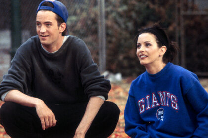 Chandler and Monica on a field sitting next to each other