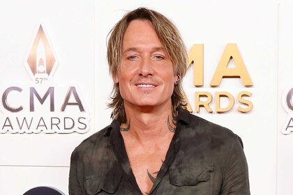 Keith Urban smiles in a black shirt on the red carpet for the 2023 CMA Awards