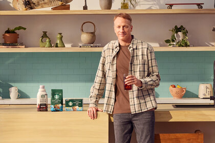 Tony Hawk stands next to starbucks coffee productcs in a kitchen for a collab with starbucks