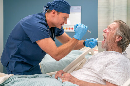 Dr Bruce looks inside a patients mouth on the pilot episode of st. denis medical