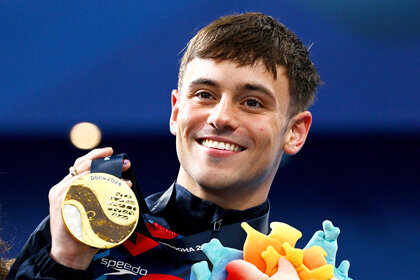 Tom Daley holds up a gold medal after a diving event