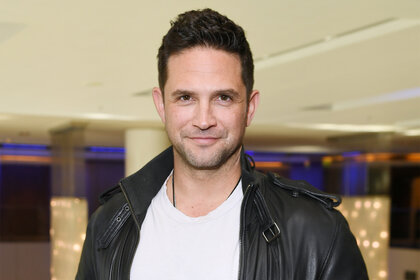 Brandon Barash wears a leather jacket and white shirt at a fan event