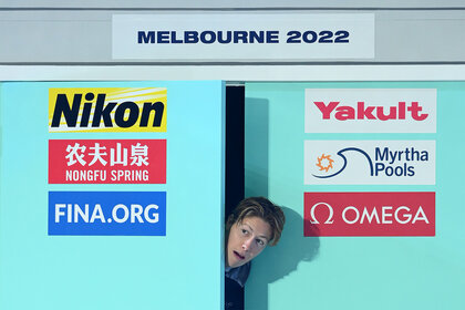 Henrik Christiansen peeks his head through a door at a swim meet