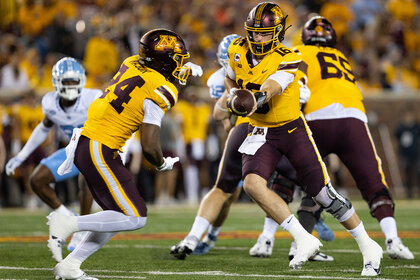 Minnesota Golden Gophers quarterback Max Brosmer hands the ball off to running back Marcus Major