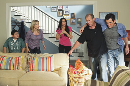 The cast of modern family are all in the dunphy living room where Jay is holding Phil