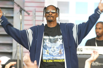 Snoop Dogg holds his hands up while performing on stage