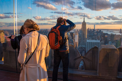 Rockefeller Center vantage point full of tourists at sunset, with the visitors overlooking the New York City skyline.