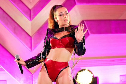 Charli XCX performs in a red outfit onstage.