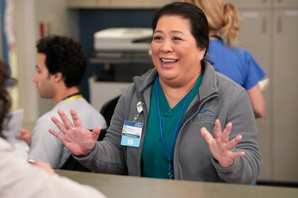 Val holds her hands up and looks happy on St. Denis Medical Season 1 Episode 1.