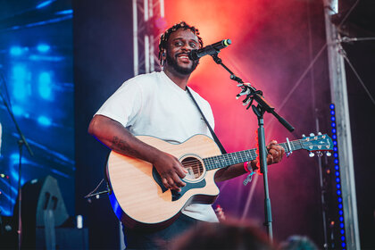 Myles Smith smiling and performing on stage.