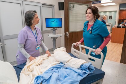 Alex and Debbie stand in front of a hospital bed on St. Denis Medical Season 1 Episode 5