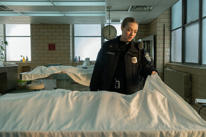 Mickey holds a sheet over a body in Long Bright River Season 1, Episode 1.