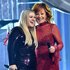 Kelly Clarkson and Reba McEntire hugging on stage.