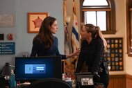 Kim Burgess and Hailey Upton speak in front of flags and badges in the police office in Chicago P.D. Episode 1102
