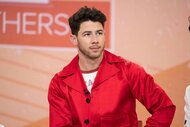 Nick Jonas smiles in a red outfit.