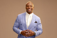 Terry Crews smiles in a blue suit for AGT Season 19