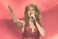Celine Dion performs on stage in a red lace dress in Los Angeles