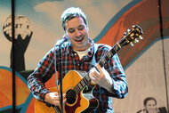 Jimmy Fallon on stage at Bonnaroo playing the acoustic guitar and singing.