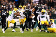 Jalen Hurts #1 of the Philadelphia Eagles stiff arms Rudy Ford #20 of the Green Bay Packers during an NFL football game