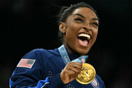 Simone Biles cheering while holding a gold medal at the Paris 2024 Olympics.