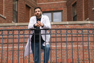 Dr Oliver Wolf leans on a railing outside of a brick building on Brilliant Minds 101