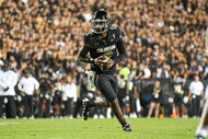 Shedeur Sanders of the Colorado Buffaloes running with a football during a game.