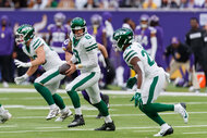 Aaron Rodgers and Breece Hall of the New York Jets during a play on the field.