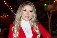 Bianca Ryan wears a red coat and smiles at a tree lighting ceremony