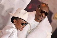 Shante Broadus and Snoop Dogg smile together in matching all-white outfits.