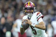 Jayden Daniels holds the ball on the football field during a game