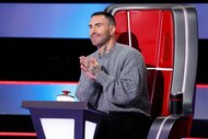 Adam Levine clapping and smiling in the coaches chair on The Voice Season 27, Episode 1.