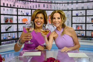 Hoda Kotb and Kathie Lee Gifford raise glasses and smile in purple dresses.