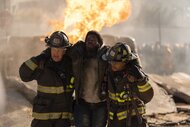 Randy "Mouch" McHolland (Christian Stolte) and Darren Ritter (Daniel Kyri) carry an injured man away from a fire in Chicago Fire Episode 1311.