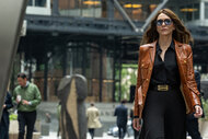 Kathryn St Jean wears a brown leather jacket in the city in Black Bag