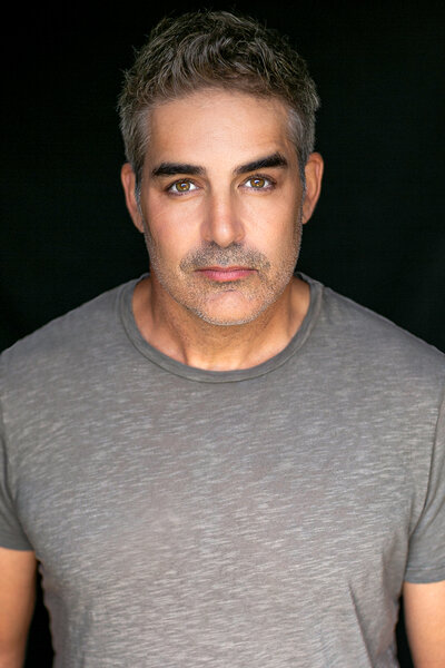 Galen Gering wears a grey t-shirt in front of a black backdrop