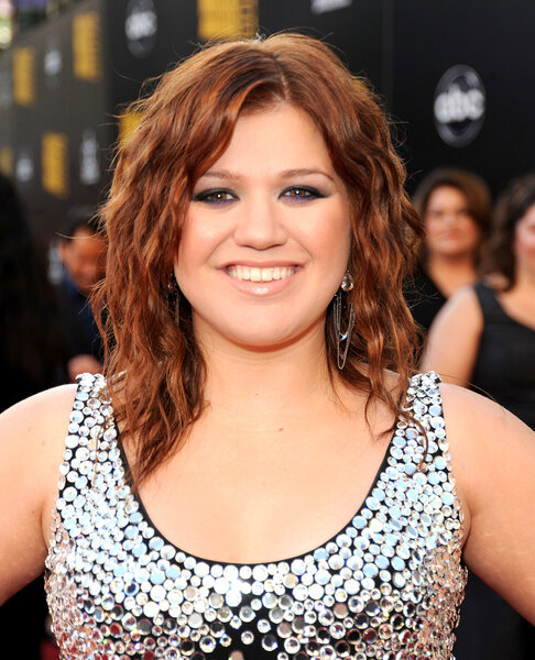 Kelly Clarkson smiles on the red carpet with reddish brown hair in 2009