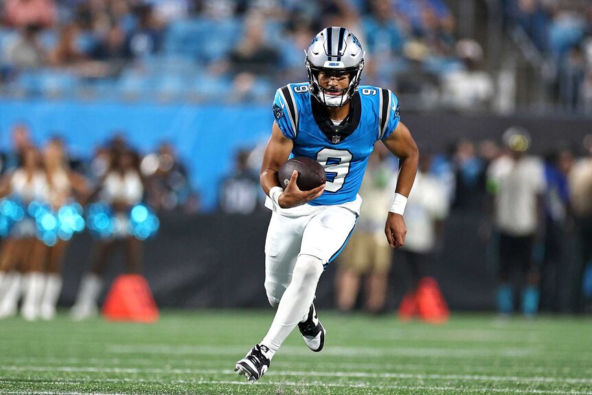 Carolina Panthers Bryce Young carrying the ball for yardage.