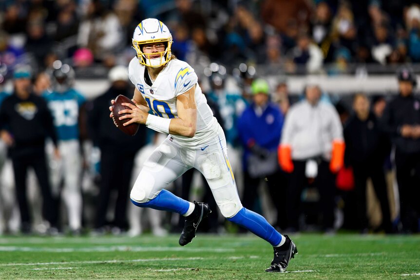 Los Angeles Chargers Justin Herbert scrambles during a football game.