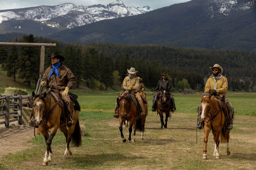 Four men ride horses on a ranch