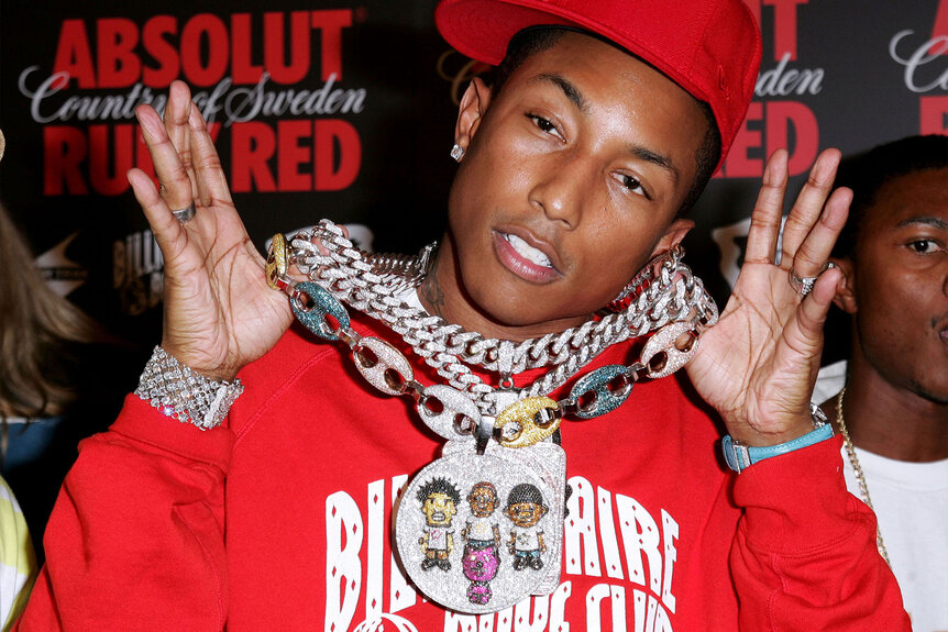 Pharrell Williams holds up his large diamond chain