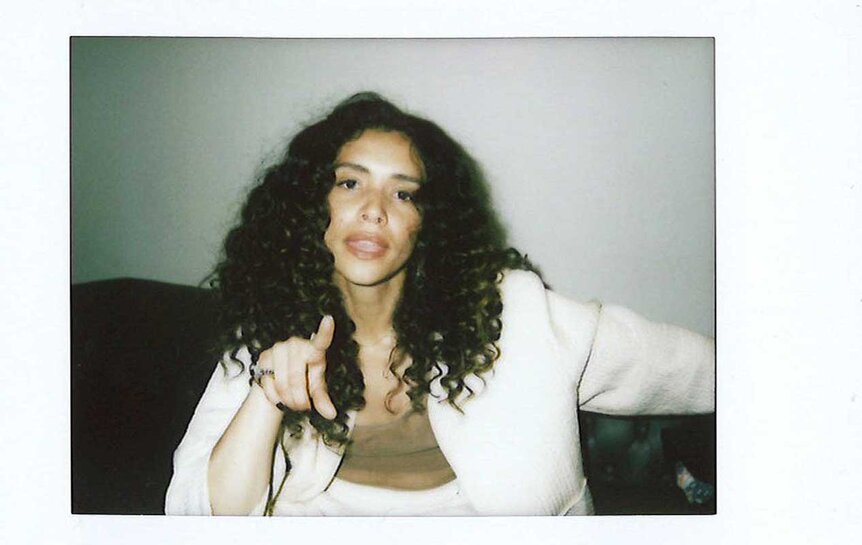 An instax of Miranda Rae Mayo pointing in a white suit