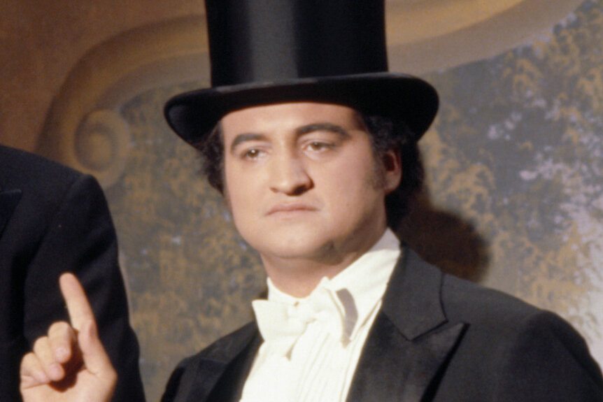 John Belushi wears a suit and tophat on Saturday Night Live Episode 219.