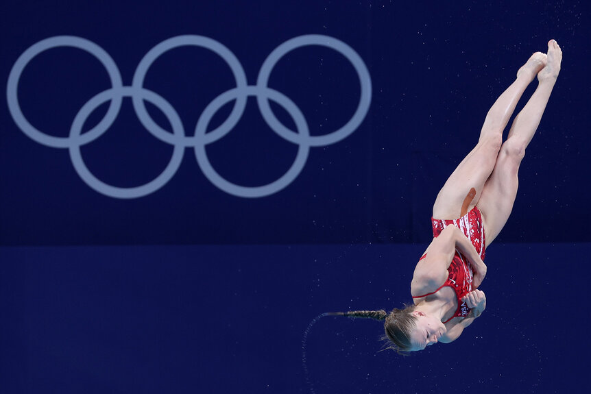 Hailey Hernandez dives with the Olympics logo in the background.