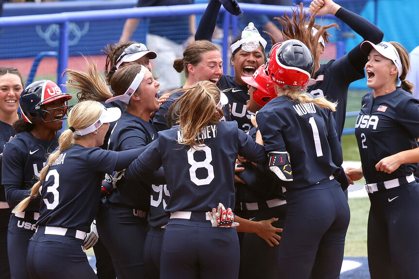 Team United States players celebrate with teammate Kelsey Stewart #7 after she hit a walk-off home run