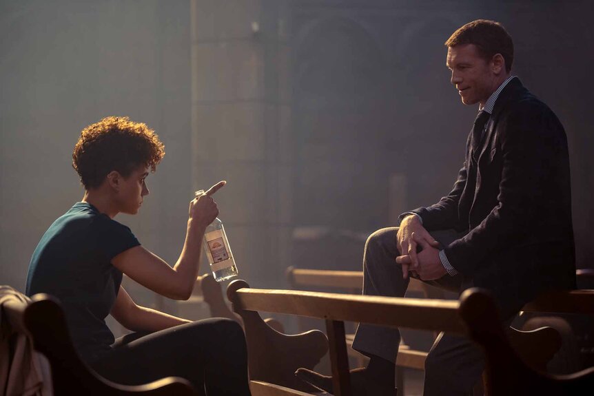 Zee (Nathalie Emmanuel) holds a bottle and points to Finn (Sam Worthington) in The Killer (2024).