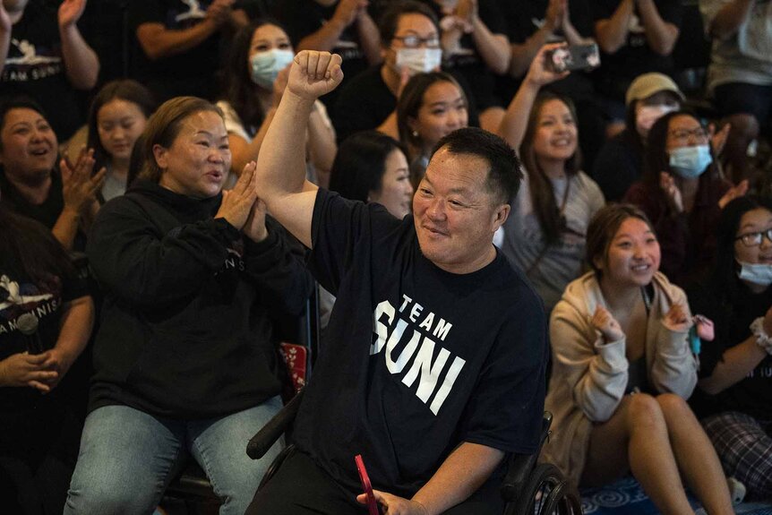 John Lee raises his arm while wearing a Team Suni shirt.